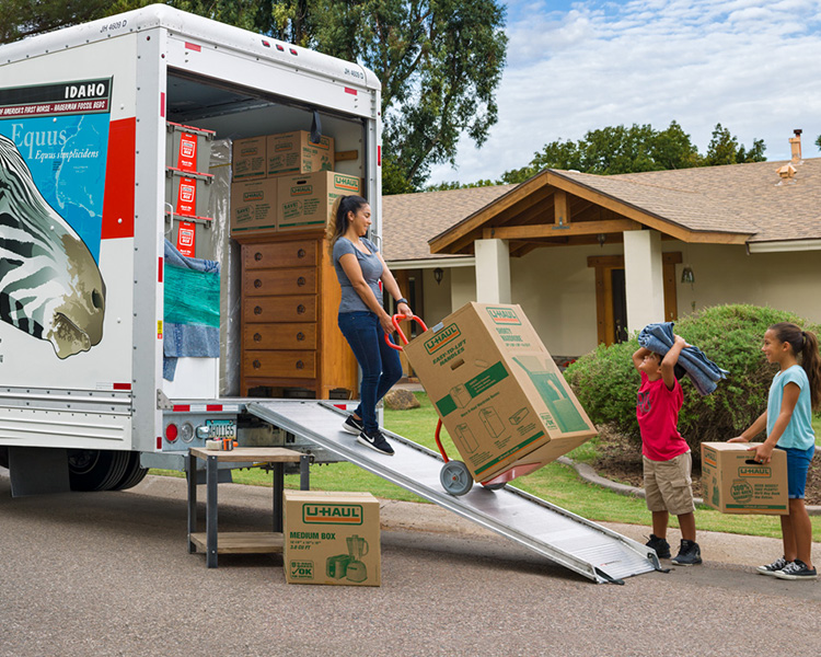 Family unloading U-Haul moving truck in front of home